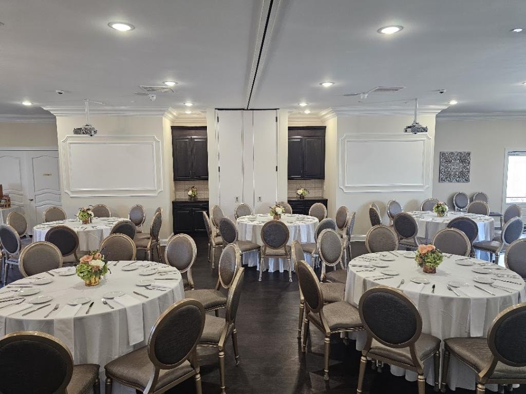 Wisteria event venue with banquet tables, formal place settings, and ceiling-mounted audiovisual equipment