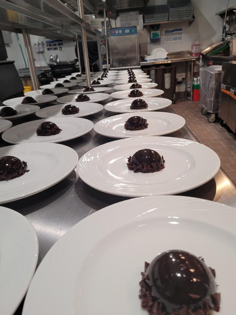 Chocolate desserts plated along a commercial kitchen pass