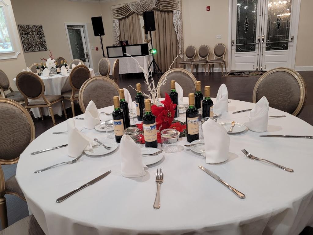 Wisteria facility arranged for a catered event with round tables, wines, and DJ equipment