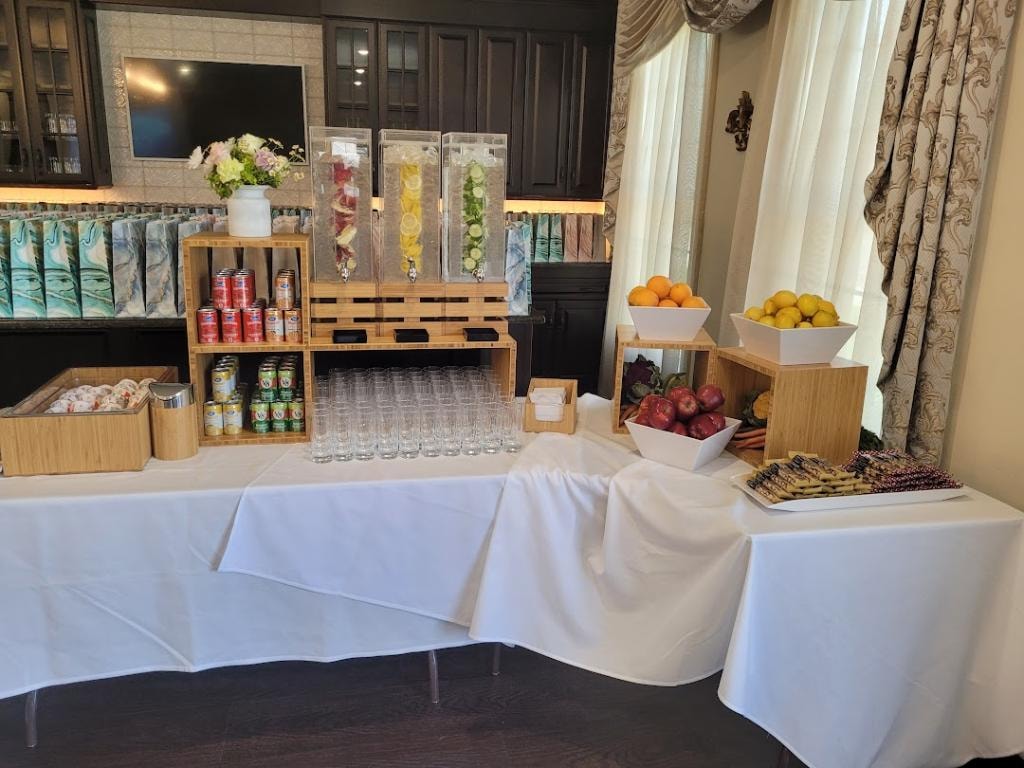Refreshment buffet with fruit, beverages, and floral decor