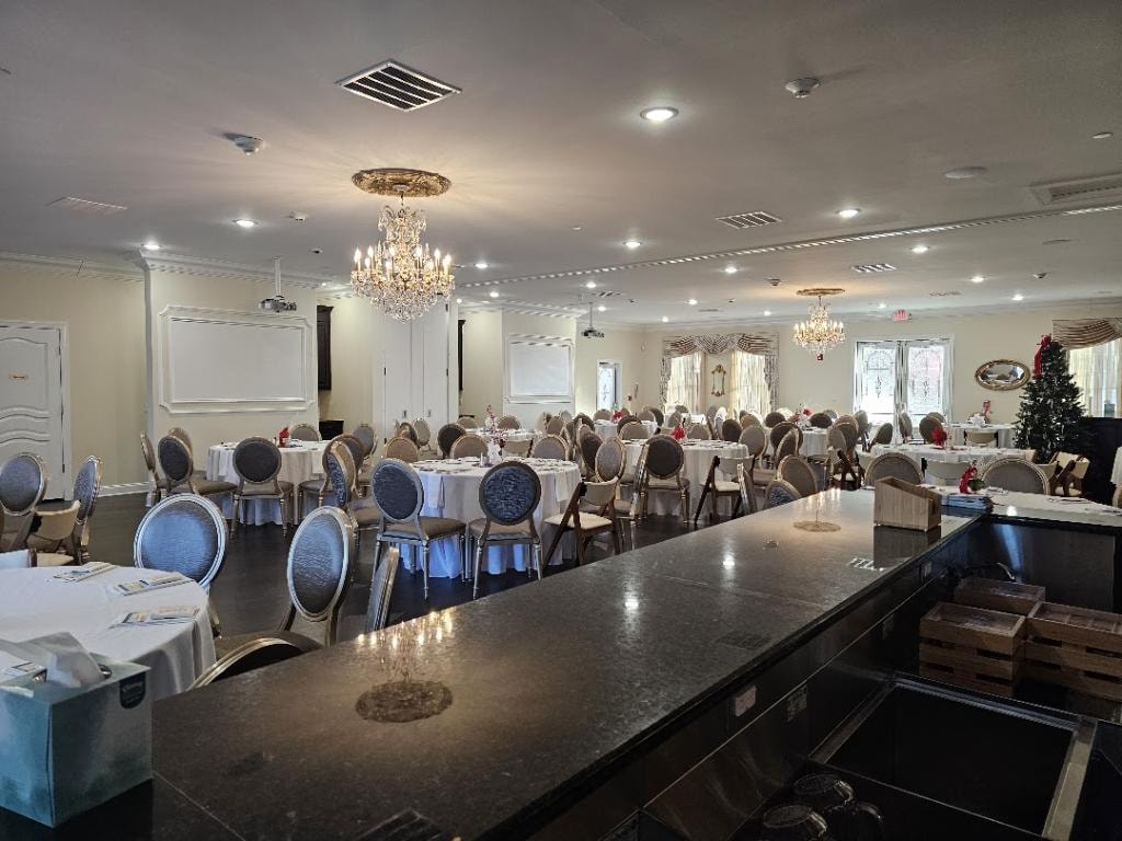 Wisteria event venue with elegant dining tables, chandeliers, service bar, and presentation screens