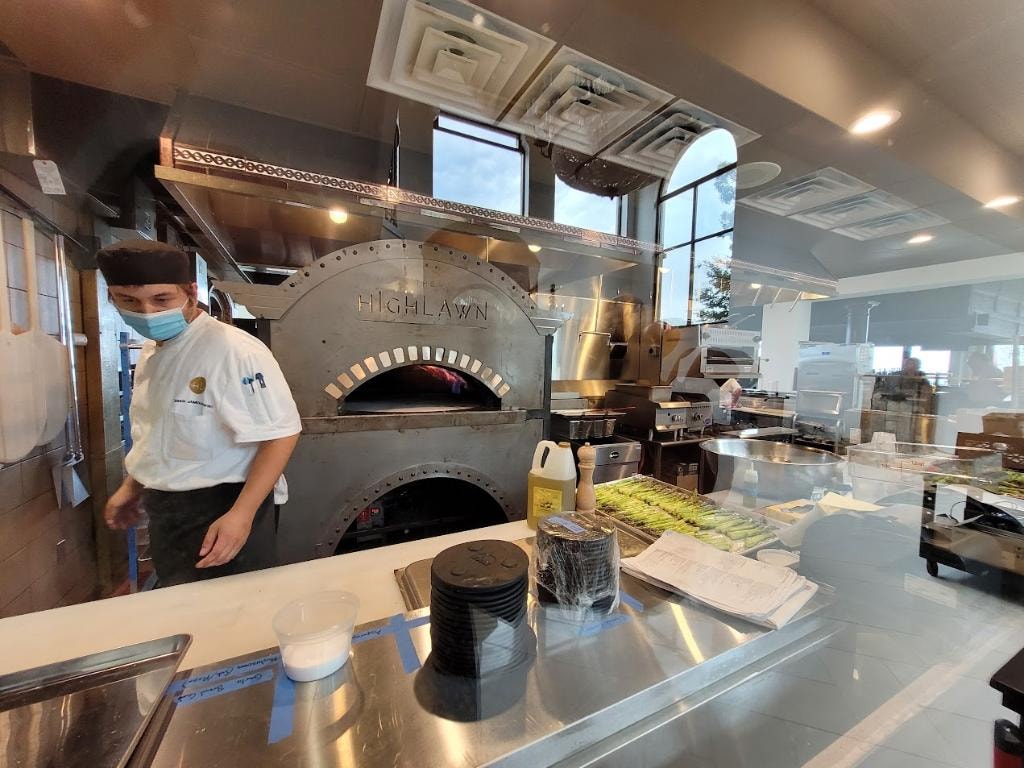 Chef working wood-fired pizza oven in kitchen