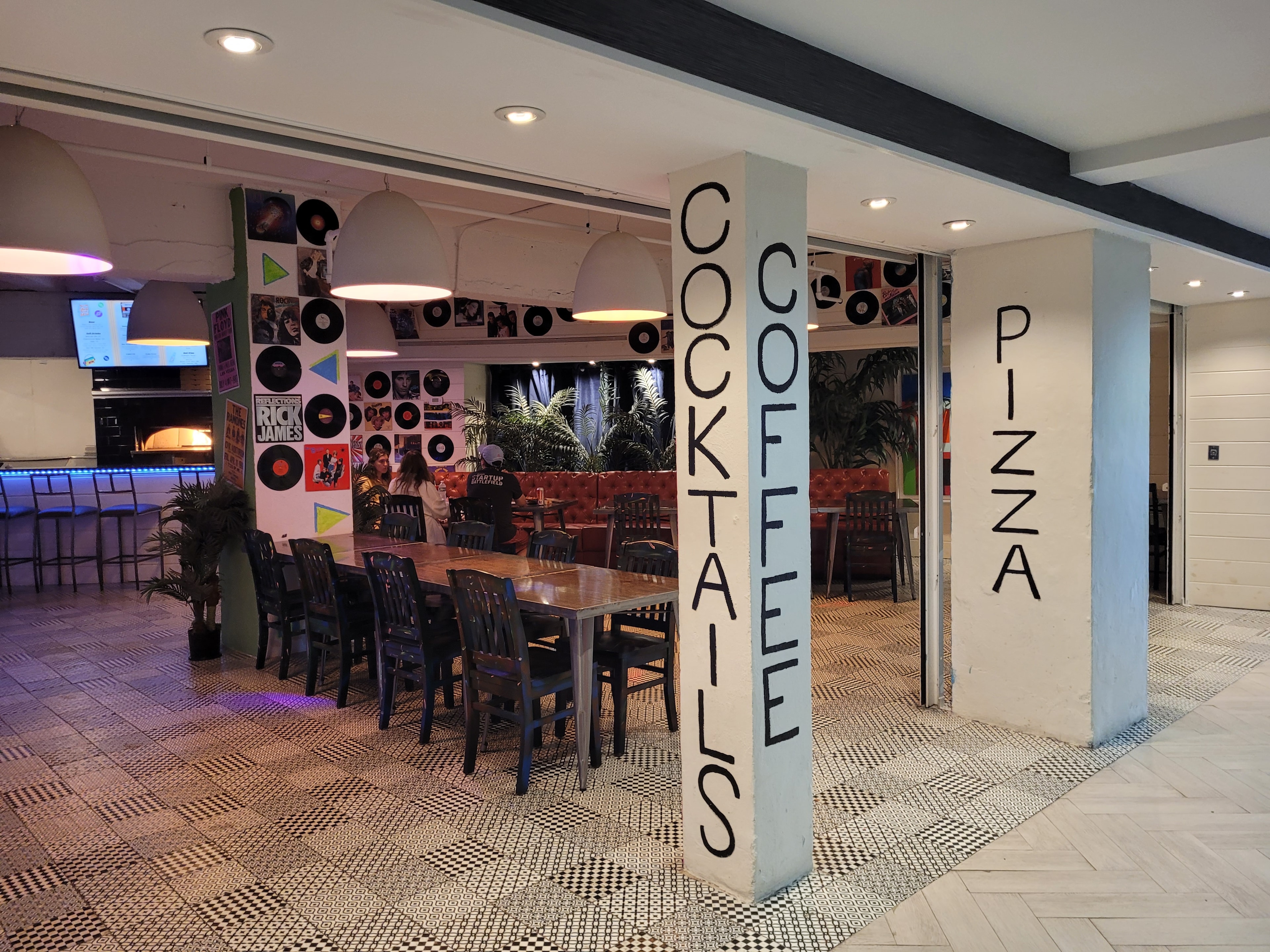 Rewind Pizzarama interior with vinyl record decor and cocktails coffee pizza columns