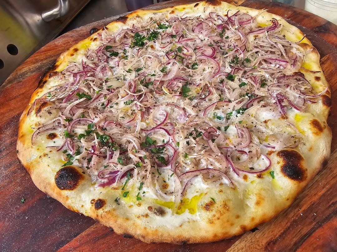 Wood-fired pizza with red onions and herbs