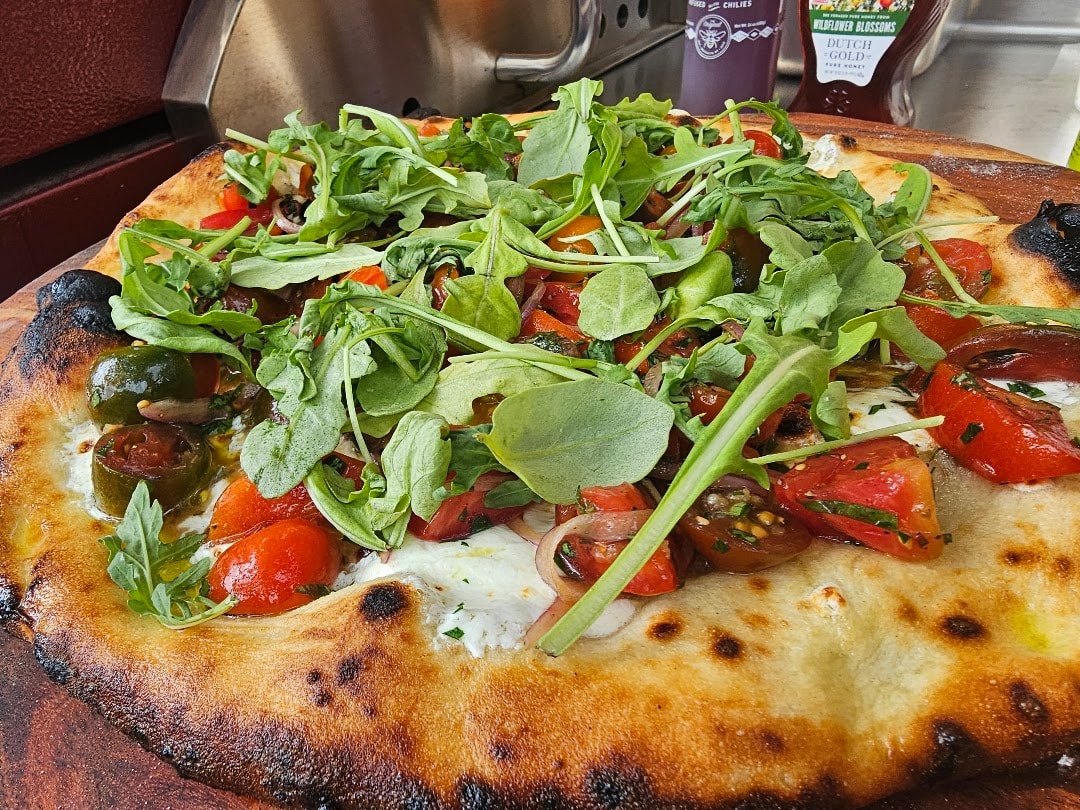 Wood-fired pizza with fresh arugula and peppers